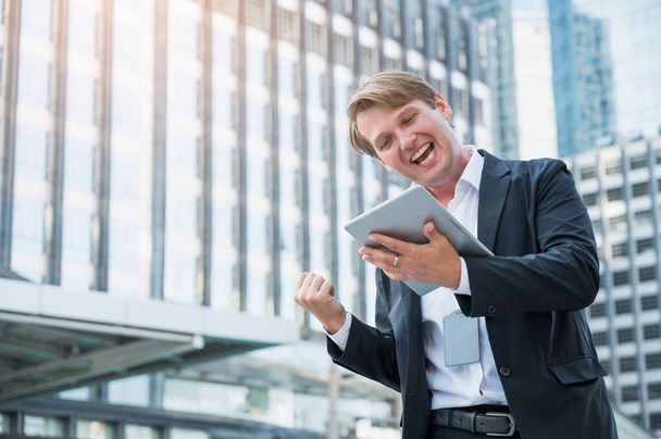 Jeune homme d'affaires se sentant heureux célébration avec la main et tenant tablette
 - Photo, image