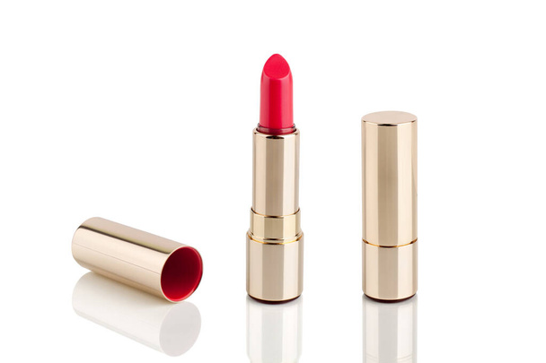 Red lipstick in golden tube on white background with mirror reflection on glass surface isolated close up, shiny gold lipstick package, open and closed lipsticks box, luxury cosmetic accessory set - Photo, Image