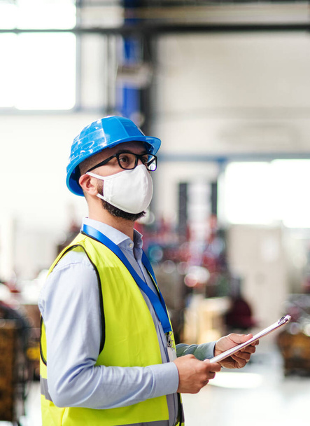 Technician or engineer with protective mask and helmet working in industrial factory. - 写真・画像