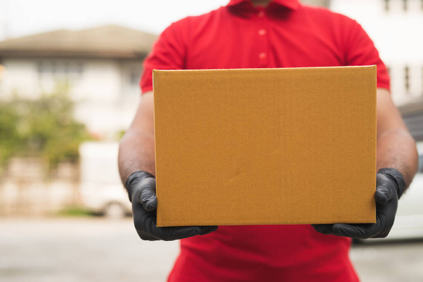 Postman в червоній формі рукавички тримає пакет
. - Фото, зображення