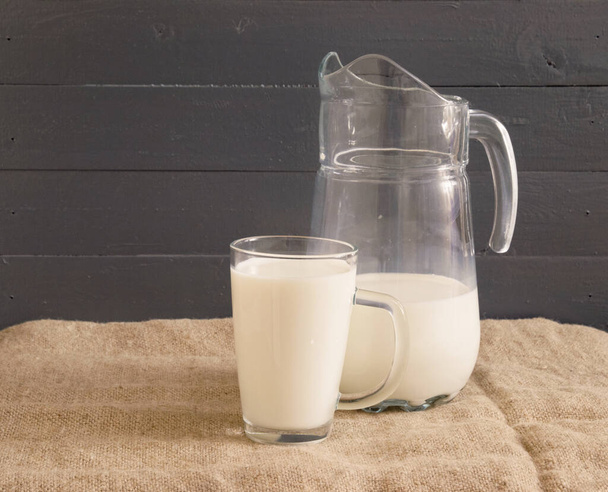 glass cup with milk and a decanter. healthy baby food. rustic background. - Photo, Image