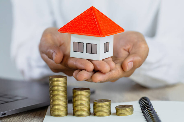 Investoren halten Häuser und Geld, Immobilien, Immobilieninvestitionen und Haus Hypothekenkonzept von Geldhäusern aus den Münzen. - Foto, Bild