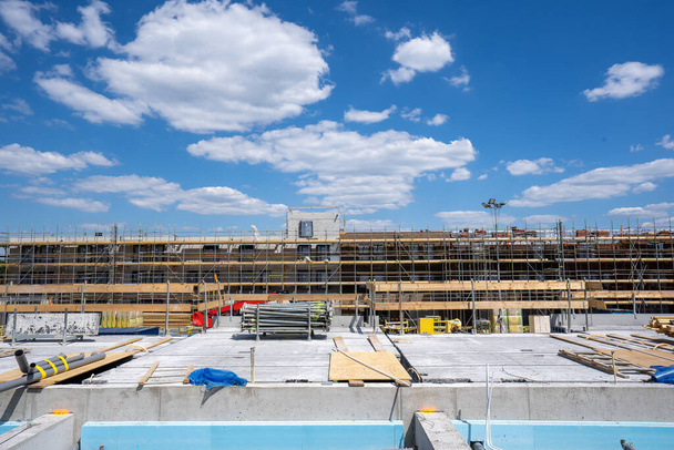 Überblick über eine Baustelle unter strahlend sonnenblauem Himmel. Stahlbeton wird gebaut und Gerüste sind sichtbar - Foto, Bild