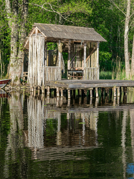 kevät maisema puinen kalastajan mökki ja puinen kävelysilta rannalla järven, kauniita heijastuksia rauhallinen järvi vesi
 - Valokuva, kuva