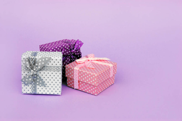 Három ajándék rózsaszín háttérrel. Jelen doboz, díszítés ajándék színes asztalon, felülnézet másolási hellyel. - Fotó, kép