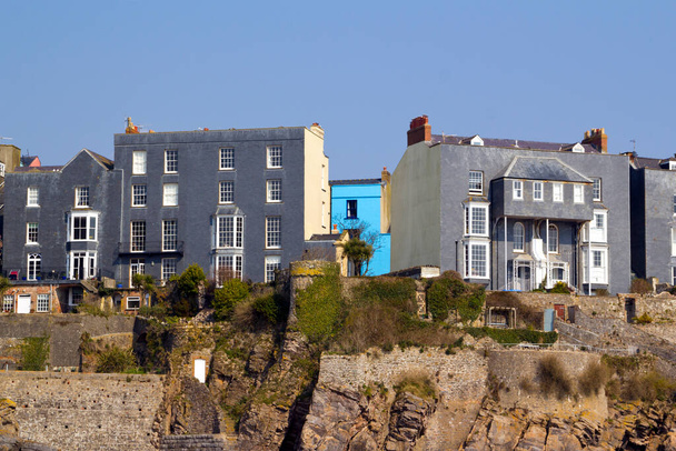 Canlı, mavi boyalı bir ev, İngiltere, Tenby, Pembrokeshire, Galler 'deki kayalıkların tepesindeki gri evler arasında göze çarpıyor. - Fotoğraf, Görsel