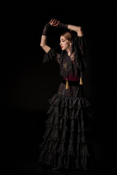 attractive dancer with hands above head dancing flamenco isolated on black - Фото, изображение