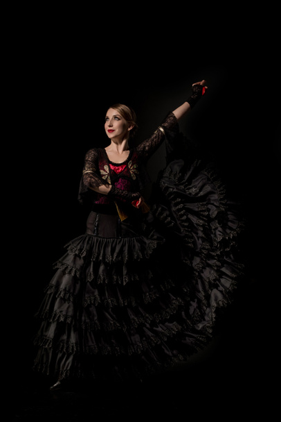 cheerful flamenco dancer in dress holding castanets and dancing isolated on black - Photo, Image