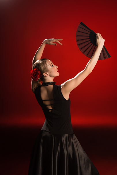 young flamenco dancer in dress looking at fan on red  - Φωτογραφία, εικόνα
