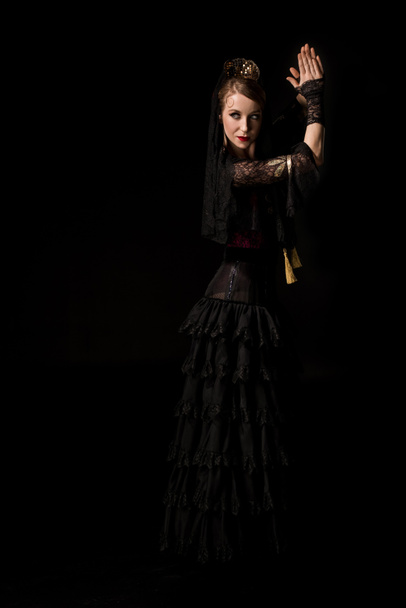 attractive young flamenco dancer dancing and clapping hands isolated on black  - Foto, Imagem