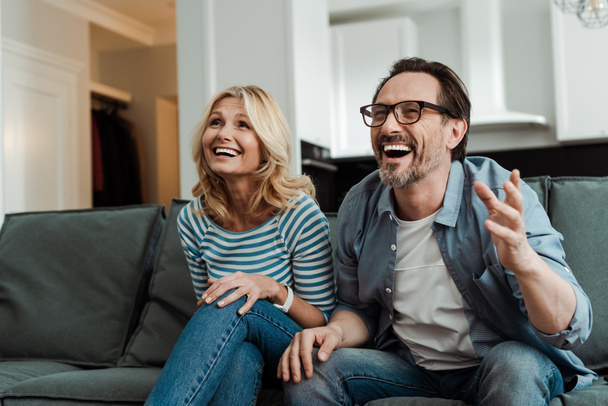 Mature couple laughing while sitting on couch   - Photo, Image