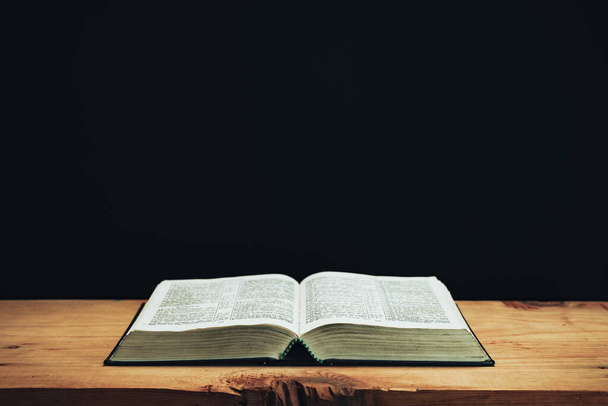 Open Holy Bible on a red old wooden table. Beautiful Black wall background.	 - Foto, Imagem