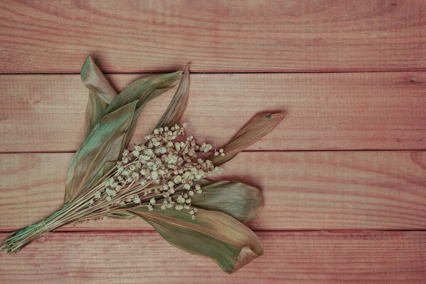 Bouquet sfumato Convallaria majalis fiori su un tavolo di legno rosso. Modello di sfondo per la progettazione.  - Foto, immagini