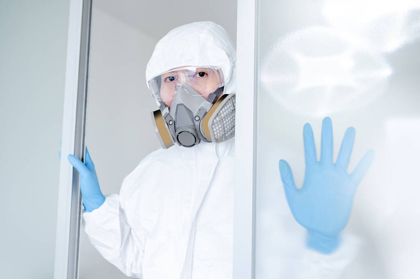 Vědec nebo Virolog muž na sobě biohazard chemické ochranné obleky, brýle a masky. Mužský lékař nebo zdravotnický pracovník používající PPE a gumové rukavice pro prevenci infekce koronavirem (COVID-19). - Fotografie, Obrázek
