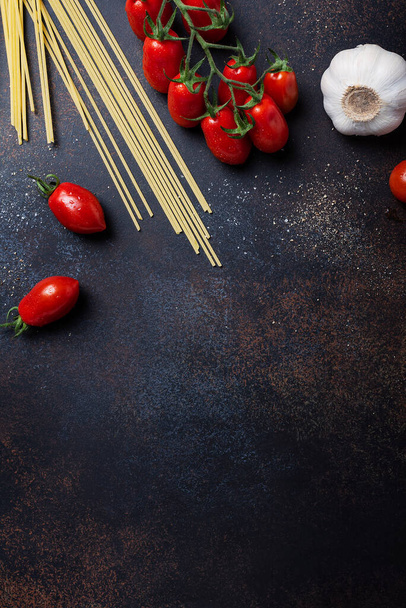 Ingredients for cooking italian pasta: spaghetti, tomato and garlic on the black table. Top view image with a copy space - Fotó, kép