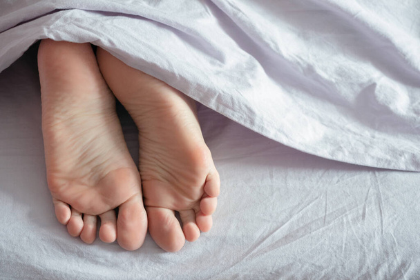 Female feet under a blanket close up. - Foto, Imagen