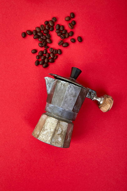 Flache Lage von Kaffeemaschine und Bohnen auf rotem Hintergrund. Kaffee-Liebe-Konzept. Mokka Kaffeekanne vorhanden. Espressomaschine vorhanden. Prozess zur Herstellung von natürlichem Kaffee aus Bohnen. Ansicht von oben. Kopierraum. - Foto, Bild