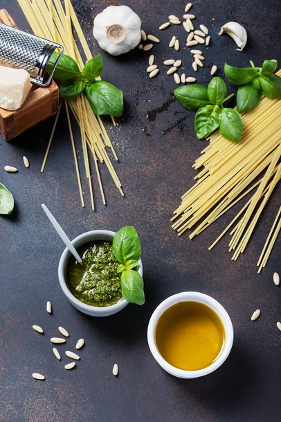Condiments for cooking italian pasta: spaghatti, basil, olive oil, garlic and pine nuts on the black table. Top view image with a copy sppace - Фото, изображение