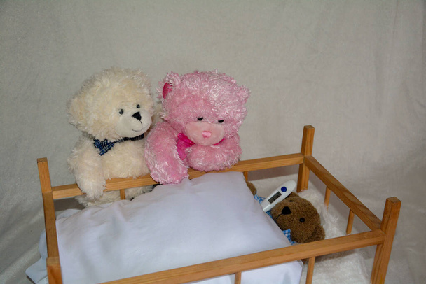Een teddybeer ouders zijn bezorgd aan het bed van hun zieke kind, teddybeer kind met klinische thermometer - Foto, afbeelding