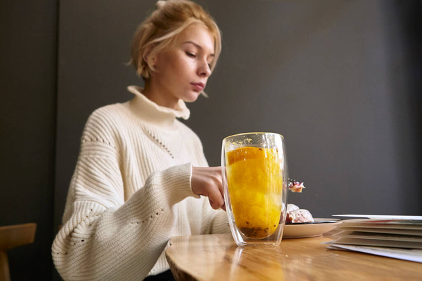 woman drinking hot tea while sitting at a table in a restaurant - Photo, Image