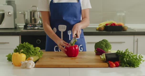 Uma mulher está a cortar uma grande pimenta no tabuleiro da cozinha. Preparação de salada. 4K
 - Filmagem, Vídeo
