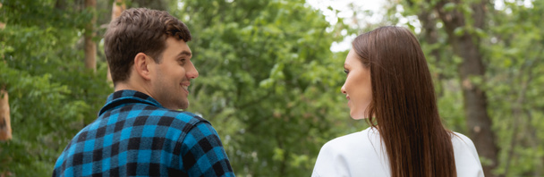 horizontal image of handsome boyfriend and pretty girlfriend looking at each other in park  - Photo, image