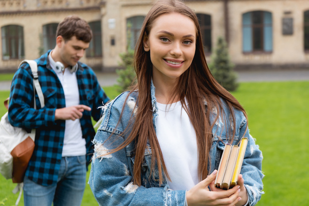 selective focus of happy girl holding books near handsome student  - Photo, Image