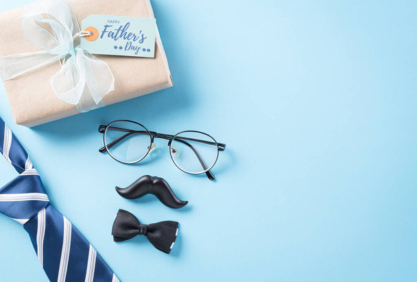 Mavi kravatlı, gözlüklü, siyah bıyıklı ve parlak pastel arka planlı hediye kutulu Mutlu Babalar Günü konsepti metin alanı. - Fotoğraf, Görsel
