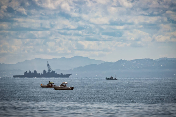 Japanische Fischerboote in der Bucht von Tokio mit einem japanischen Zerstörer und den Hügeln der Präfektur Chiba im Hintergrund. - Foto, Bild