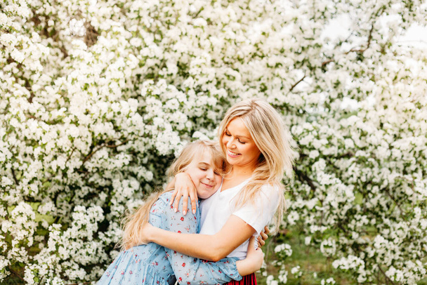 Mother and daughter in blooming trees, spring, Apple tree, flower, beauty, fashion, hugs, kisses - Photo, Image