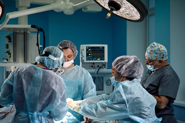 Uma equipa internacional de médicos durante uma operação real. salvar vidas, luz azul
. - Foto, Imagem