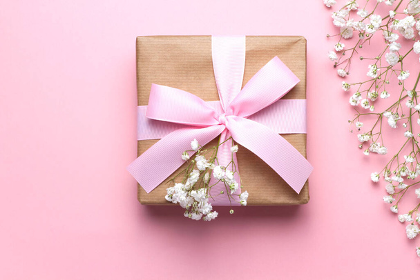 Geschenk aus Bastelpapier und Babyblumen auf rosa Hintergrund. Flache Lage, Draufsicht. - Foto, Bild