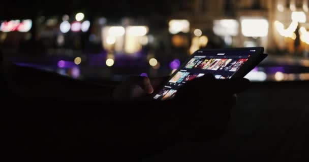 Człowiek przeglądający aplikację filmową Letterboxd z tabletu w nocy - film info app - Materiał filmowy, wideo