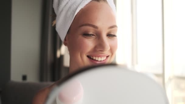 Young pleased happy woman indoors at home apply makeup with brush - Imágenes, Vídeo