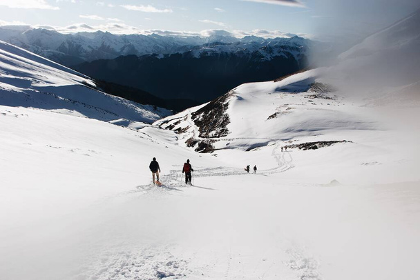 A behind shot of the hikers in the mountains covered in snow - Foto, Imagen