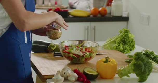 Close-up shooting. A woman is sprinkling sesame seeds on the salad. Salad preparation. 4K - Séquence, vidéo
