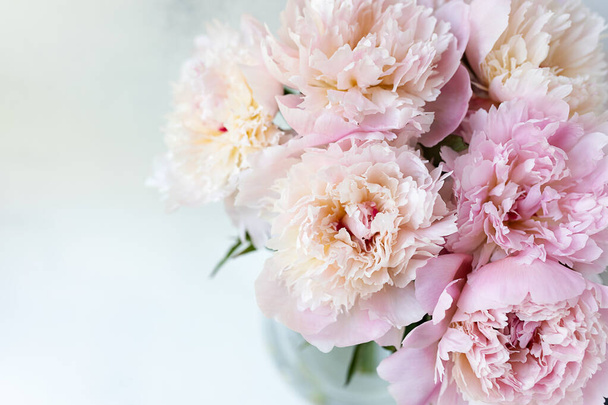 Decoratief stilleven, bloemstuk. Bruiloft of vakantie boeket van delicate roze pioen bloemen. armoedige witte tafel achtergrond. Vlakke lay, bovenaanzicht. Zomer concept. selectieve focus. - Foto, afbeelding