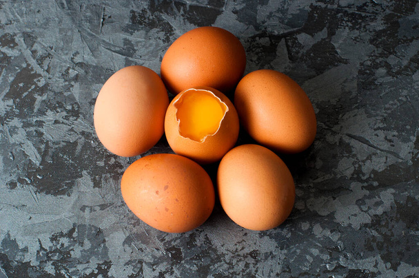 Chicken eggs on dark gray background, visible orange yolk - Photo, Image