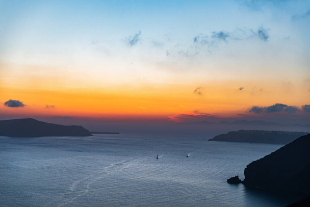 Landschaft mit Wasser und Felsen bei Sonnenuntergang. Schöne Farben. Zwei Yachten segeln in der Ferne. - Foto, Bild