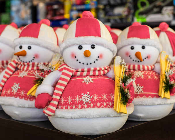 帽子のかわいいおもちゃの雪だるまとスキー付きのピンクのセーター。新年の装飾、休日のおもちゃ。雪男とクリスマスカード、クローズアップ - 写真・画像