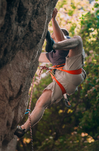 Genç erkek kaya tırmanışçısı uçurumda zorlu bir rotada - Fotoğraf, Görsel