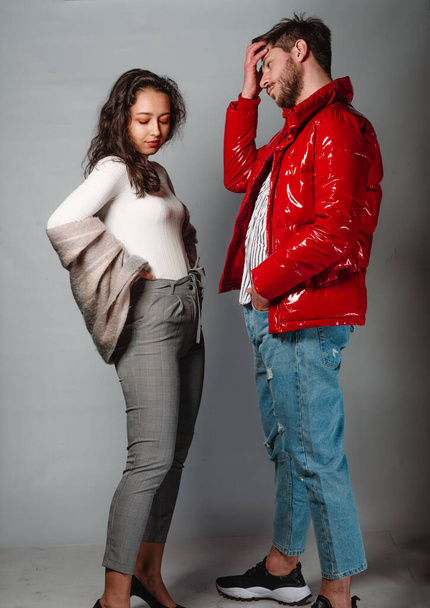 Studio fashion shot of modern guy with mont jacket and girl posing in stylish trendy clothes - Photo, Image