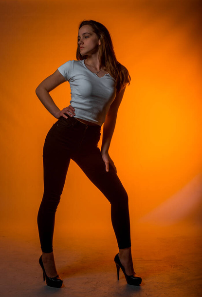Portrait of a beautiful stylish woman posing against orange background - Photo, Image