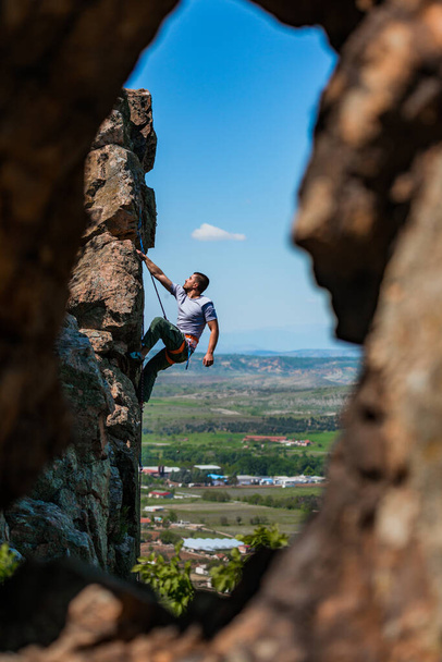 El hombre sube a la roca en el fondo de un hermoso paisaje de montaña - Foto, imagen
