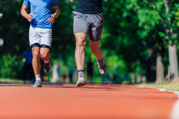 Крупные ноги с кроссовками и сильными спортивными ногами бегущего спортсмена на беговой дорожке - Фото, изображение