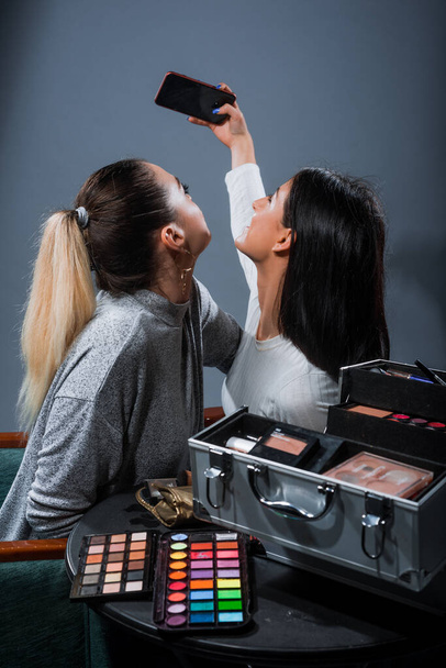 Studio shot of a stylish women posing with a professional makeup kit - Foto, imagen