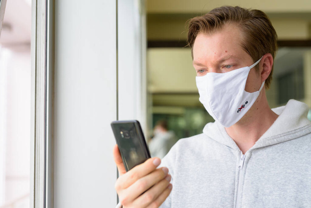 Portrait of young man wearing mask for protection from corona virus outbreak at the gym during quarantine - 写真・画像