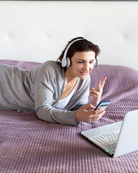 Junge glückliche Frau in Grau entspannt zu Hause und genießt Zeit für sich mit Kaffee. Freizeit mit Technik, Pastellfarben, Kopierraum - Foto, Bild