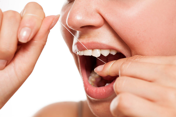  młoda kobieta myje zęby nitką dentystyczną - Zdjęcie, obraz