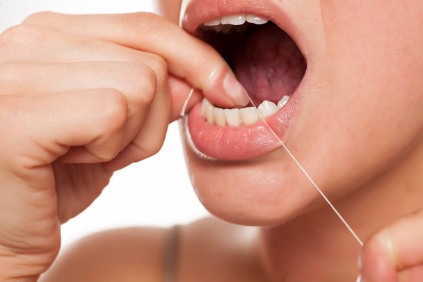  mladá žena čistí zuby zubní nit - Fotografie, Obrázek